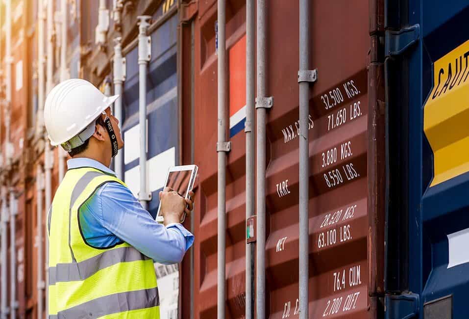 Logistics worker with a tablet checking shipping containers