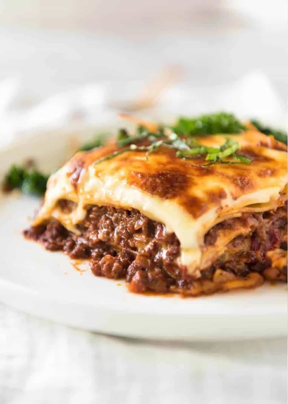 Porción de lasaña de carne horneada servida en un plato blanco