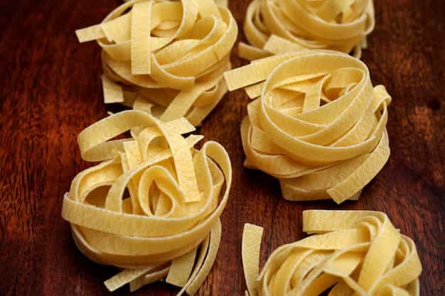 Nidos de fettuccine fresco sobre una tabla de madera