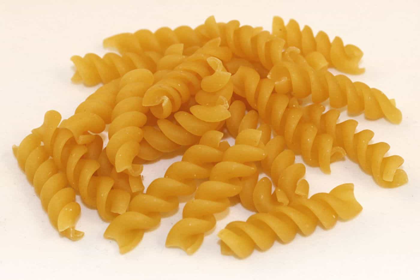 Pasta fusilli seca en espiral sobre fondo blanco
