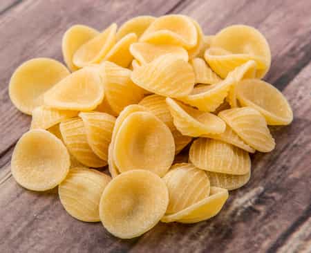 Pasta orecchiette seca sobre una mesa de madera