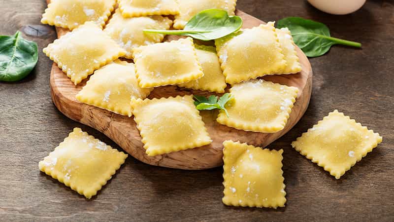 Ravioli fresco con albahaca sobre una tabla de madera