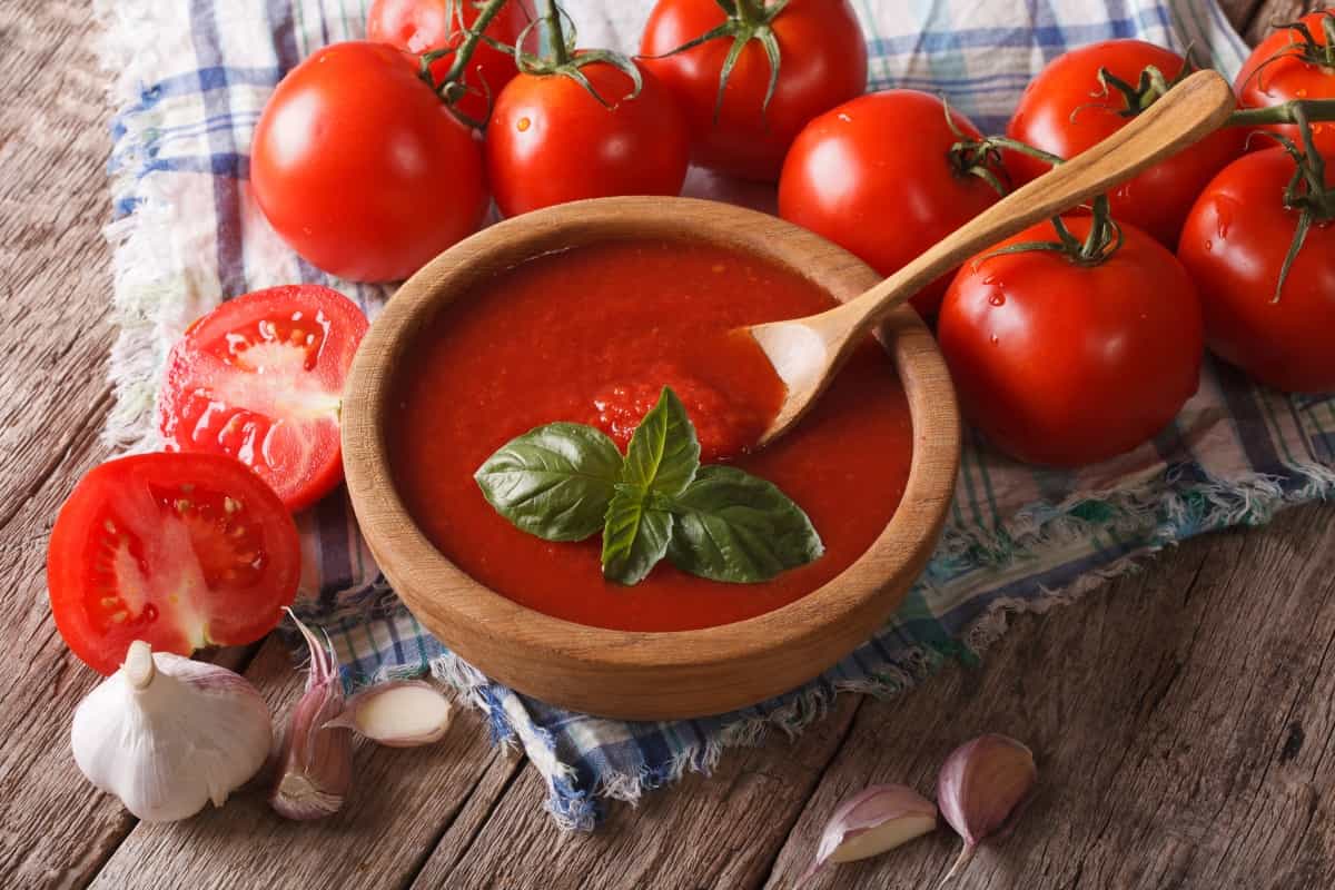 Tomates frescos y un bol de salsa de tomate con ajo y albahaca